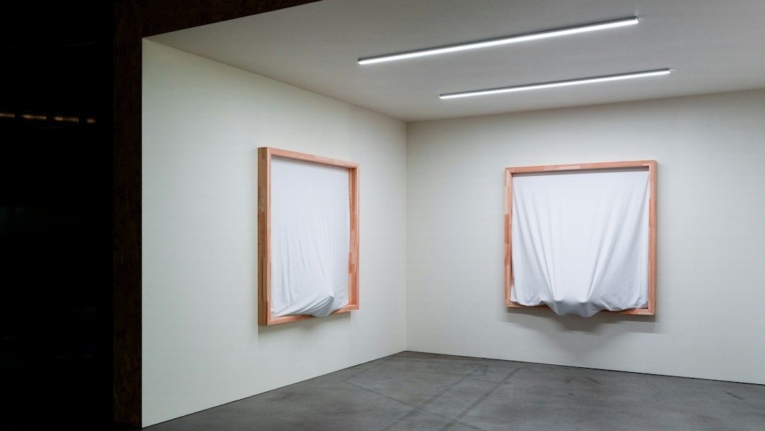 Leerer White Cube mit zwei verhüllten gerahmten Wandobjekten